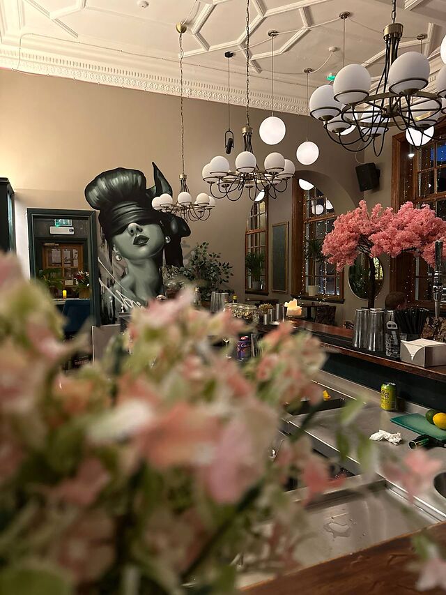 The bar, with a street-art mural, globe chandeliers and pink blossom in the foreground.