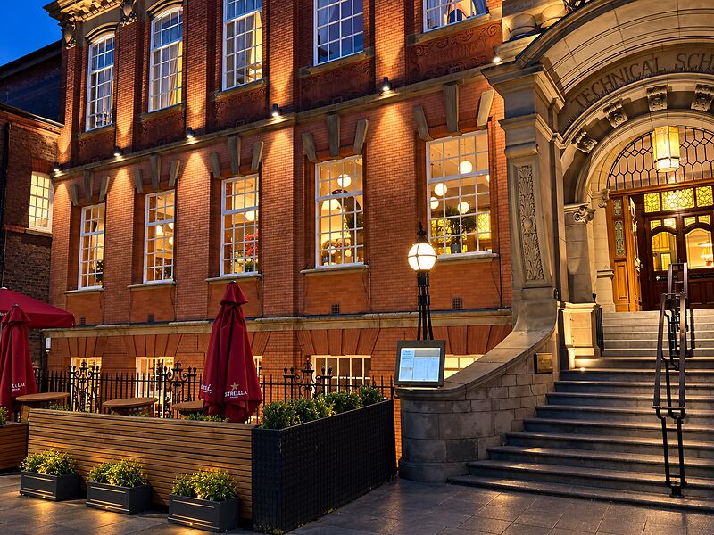 The red-brick Treasury Building on Palmyra Square South at dusk, warm light in the windows and stone steps up to the entrance.